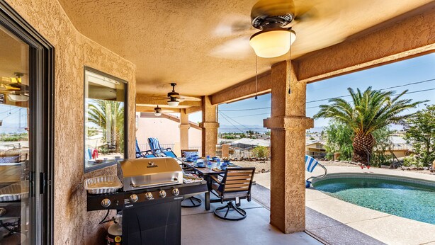 Eine Terrasse im Freien mit Grill, Esstisch, Stühlen und einem Pool.
