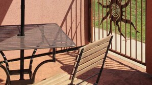 A patio with a red umbrella, a metal table, and a bench. - Best Rental in Town. (Moab)