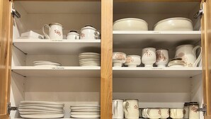 A kitchen cabinet with shelves holding plates, bowls, and mugs. A toaster is on the counter below. - Best Rental in Town. (Moab)