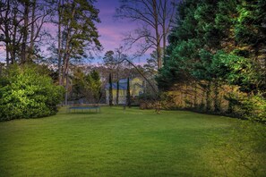 A house surrounded by a well-maintained lawn and dense trees.