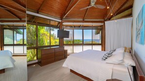 Une chambre spacieuse avec un grand lit, un plafond en bois et une vue sur l’océan.