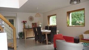 Un vaste espace de vie comprenant une table à manger, des chaises, un canapé et un escalier.
