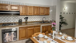 Una cocina moderna con armarios de madera, una estufa a gas y un comedor preparado para cuatro personas.