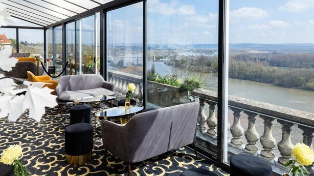 Een moderne kamer met grote ramen met uitzicht op een rivier en het omliggende landschap.