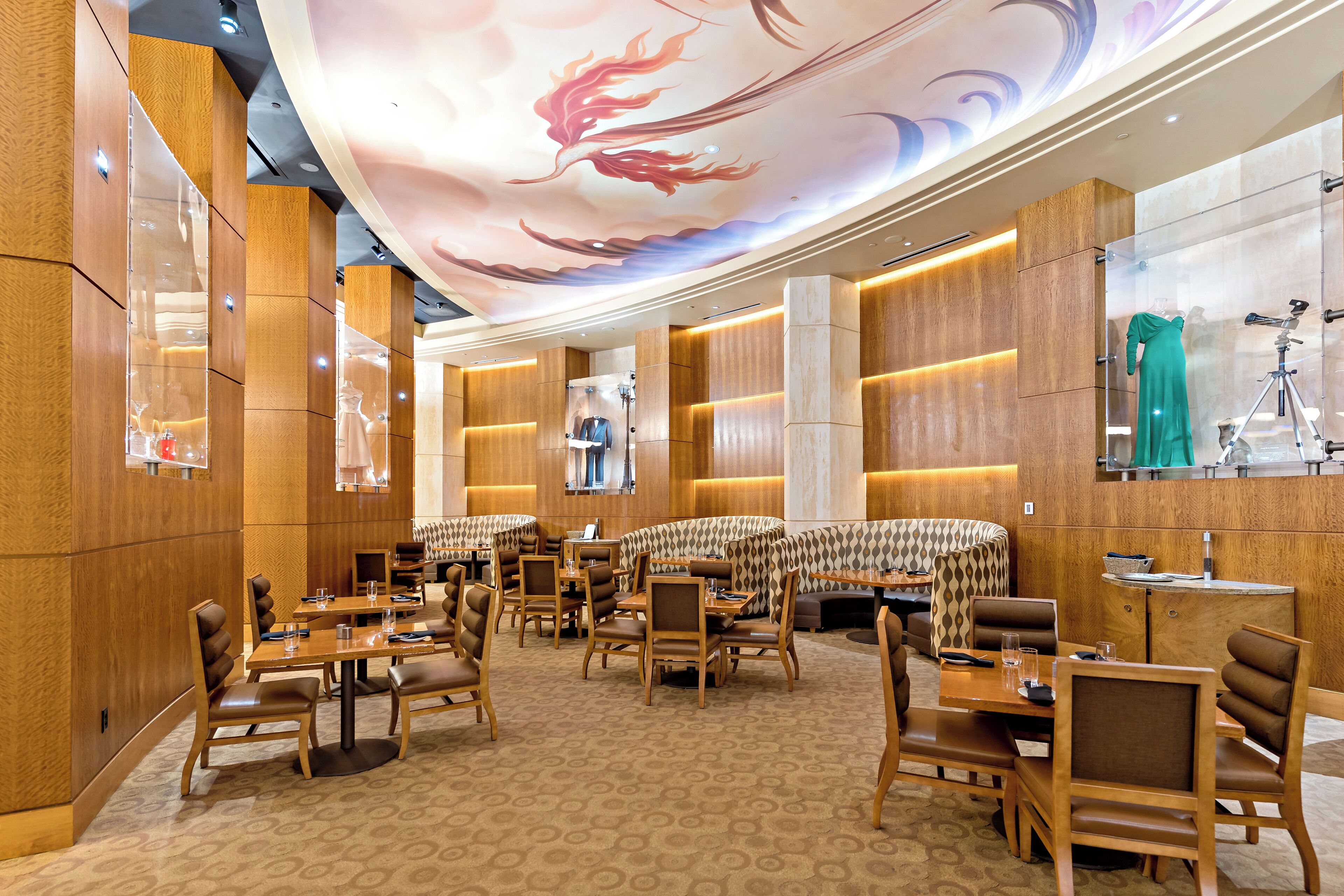 A spacious hotel lobby with wooden paneling, a patterned carpet, and a ceiling with a dragon mural.