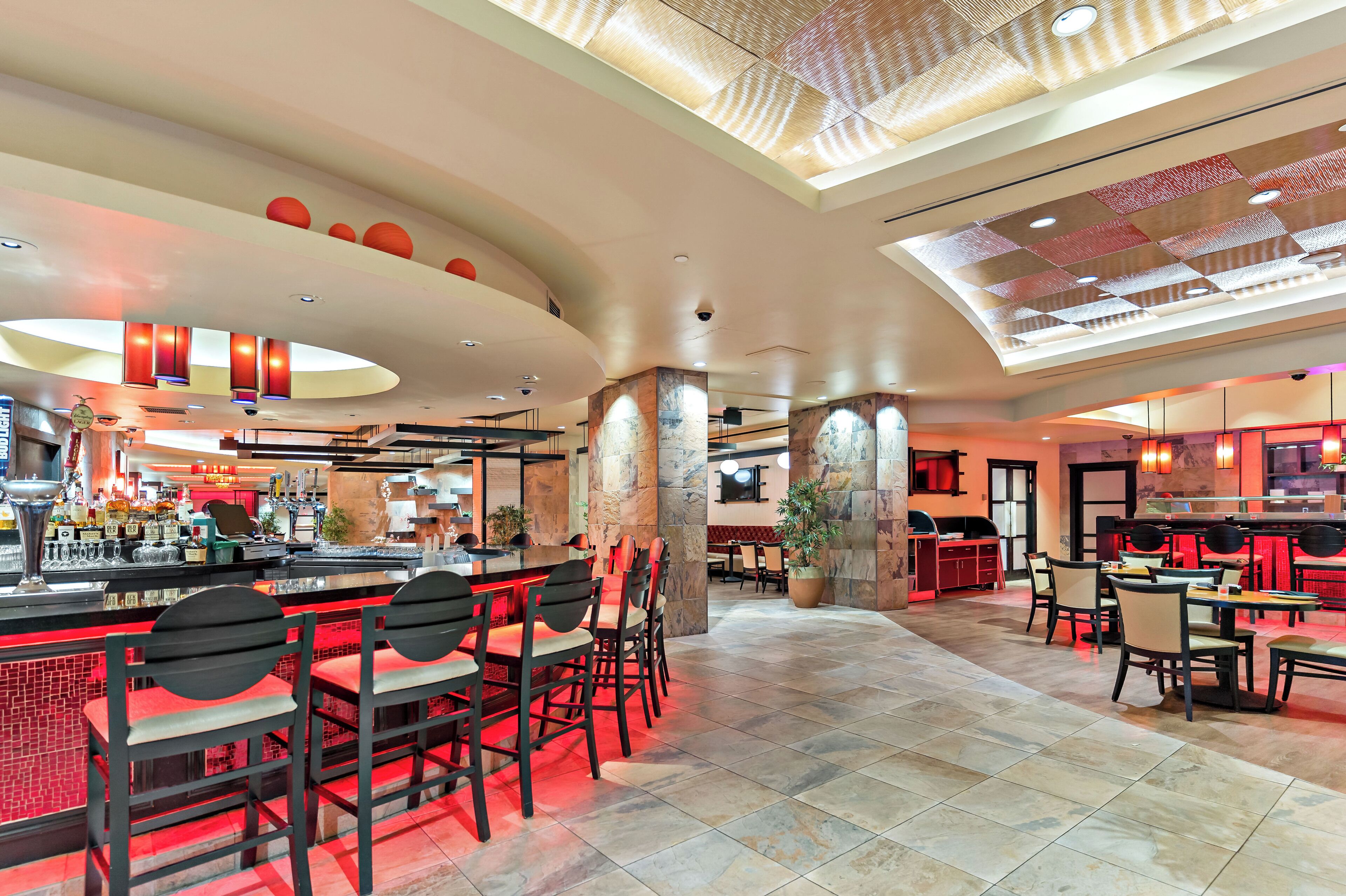 A spacious restaurant with high ceilings, a central bar area, and multiple seating arrangements.