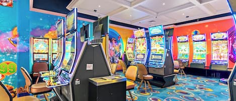 A casino with multiple slot machines, chairs, and a colorful carpet.