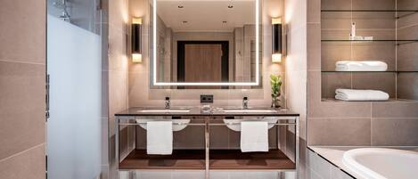 A modern bathroom with dual sinks, a large mirror, and a glass-enclosed shower.