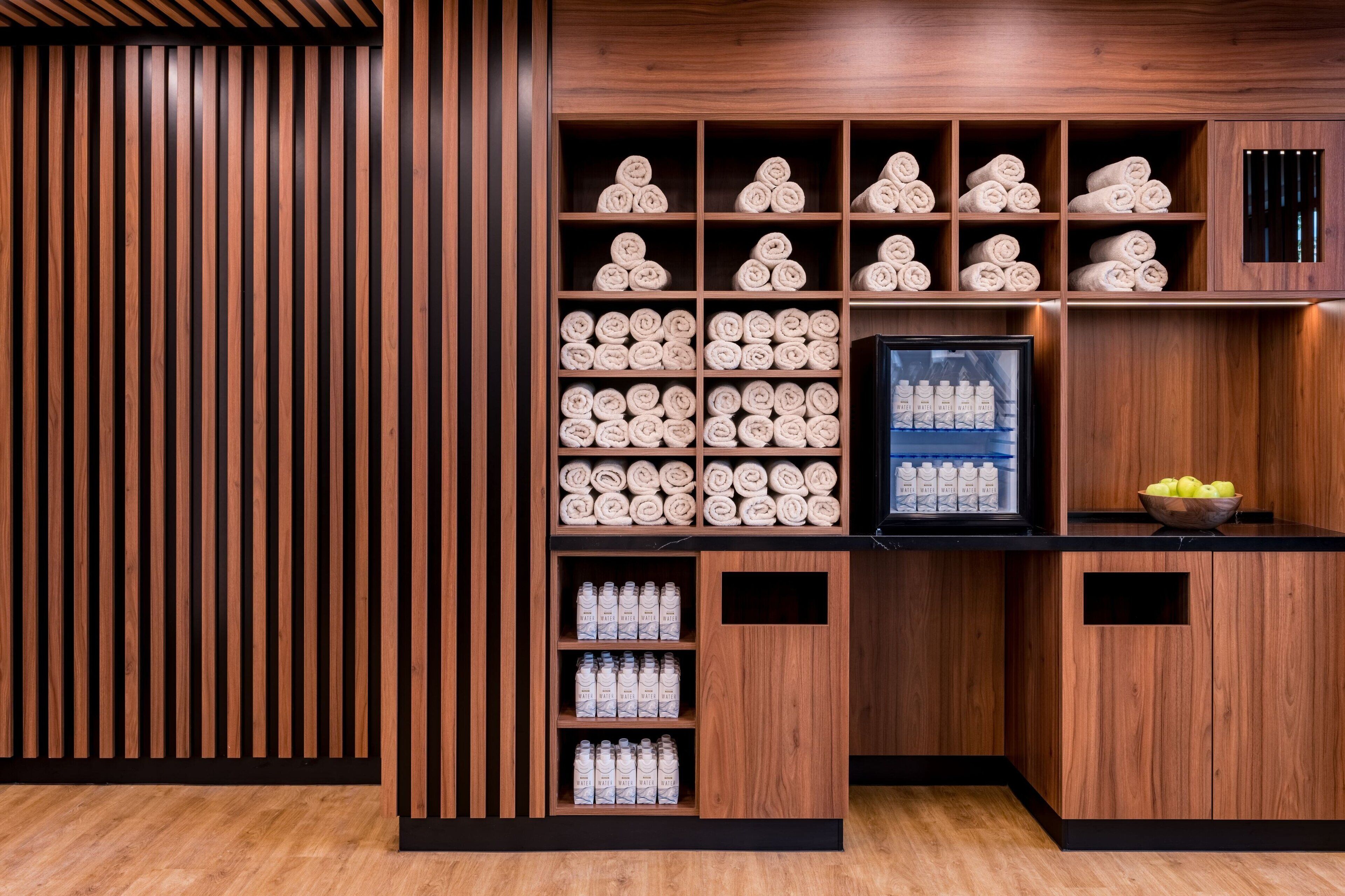 A wooden wall with shelves holding rolled towels and bottles.