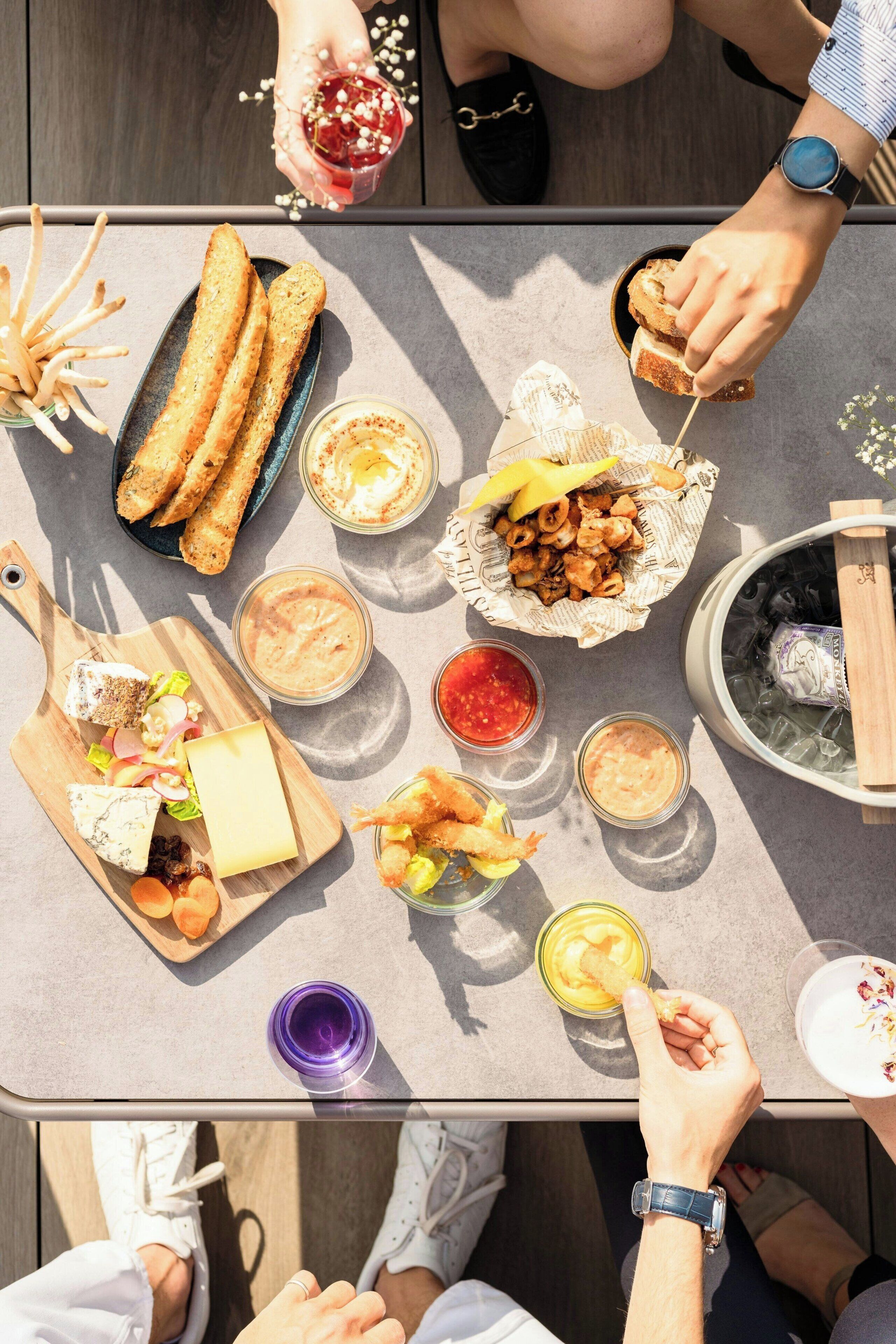Una mesa con diferentes alimentos y bebidas, como palitos de pan, camarones y una tabla de quesos.