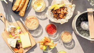 Una mesa con diferentes alimentos y bebidas, como palitos de pan, camarones y una tabla de quesos.