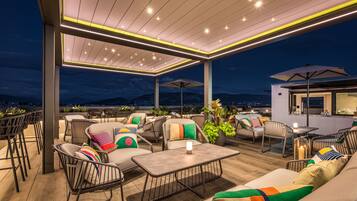 A rooftop patio with outdoor seating, a table, and a bar area.