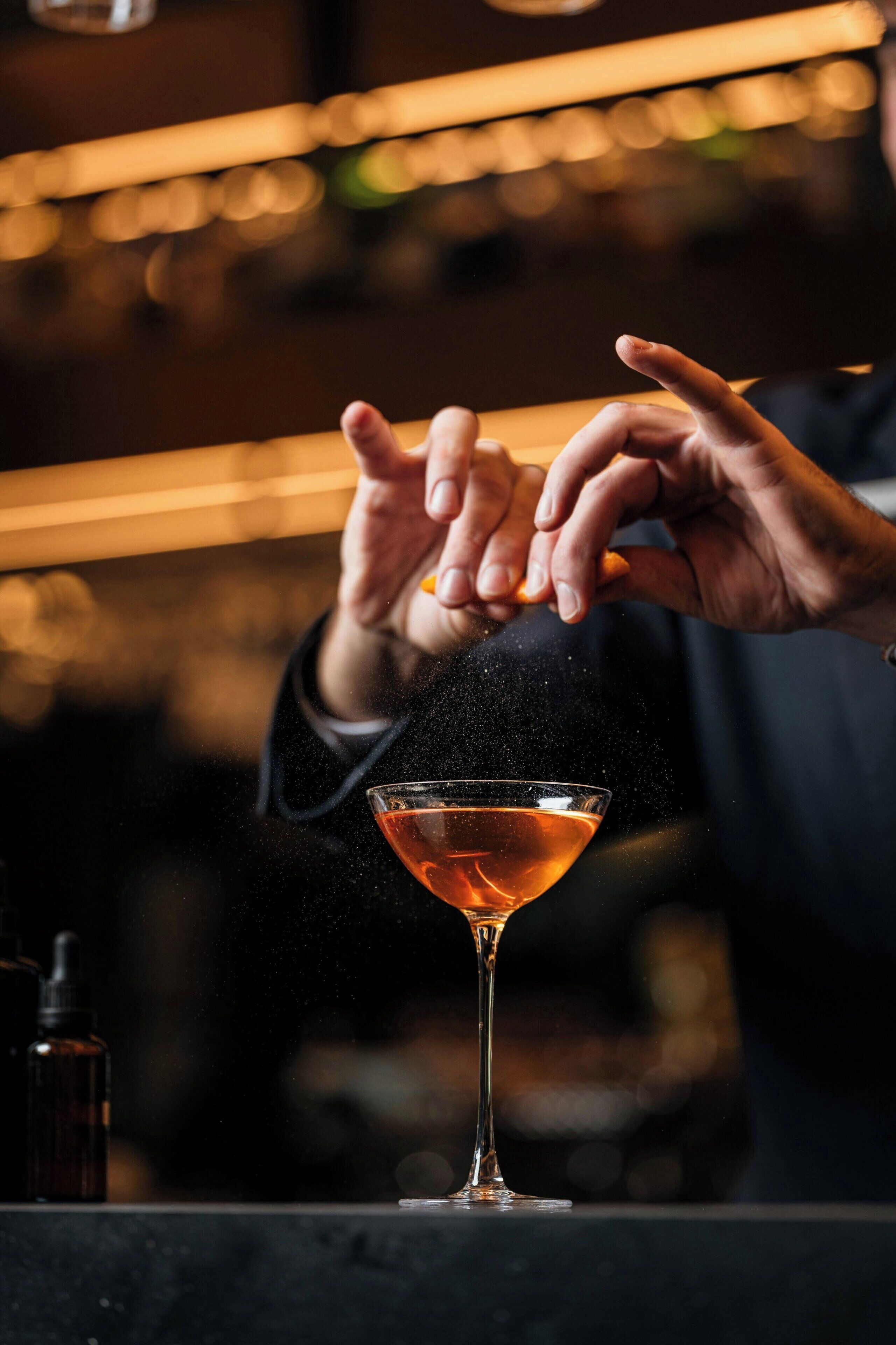 A person pouring a drink into a martini glass.