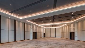 A spacious, modern hotel room with a large, carpeted floor, recessed lighting, and a minimalist design.
