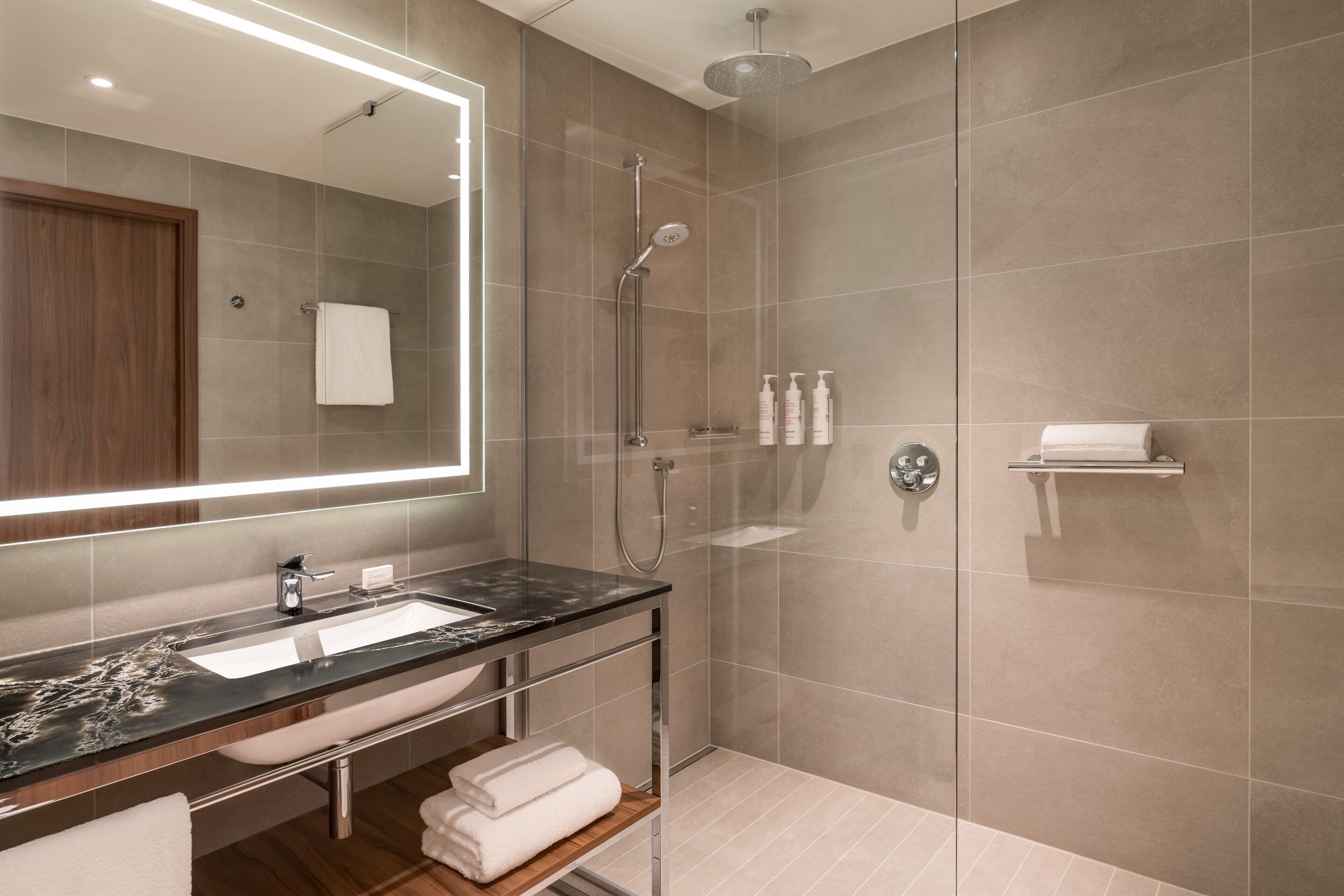A modern bathroom with a glass-enclosed shower, a vanity with a marble countertop, and a large mirror.