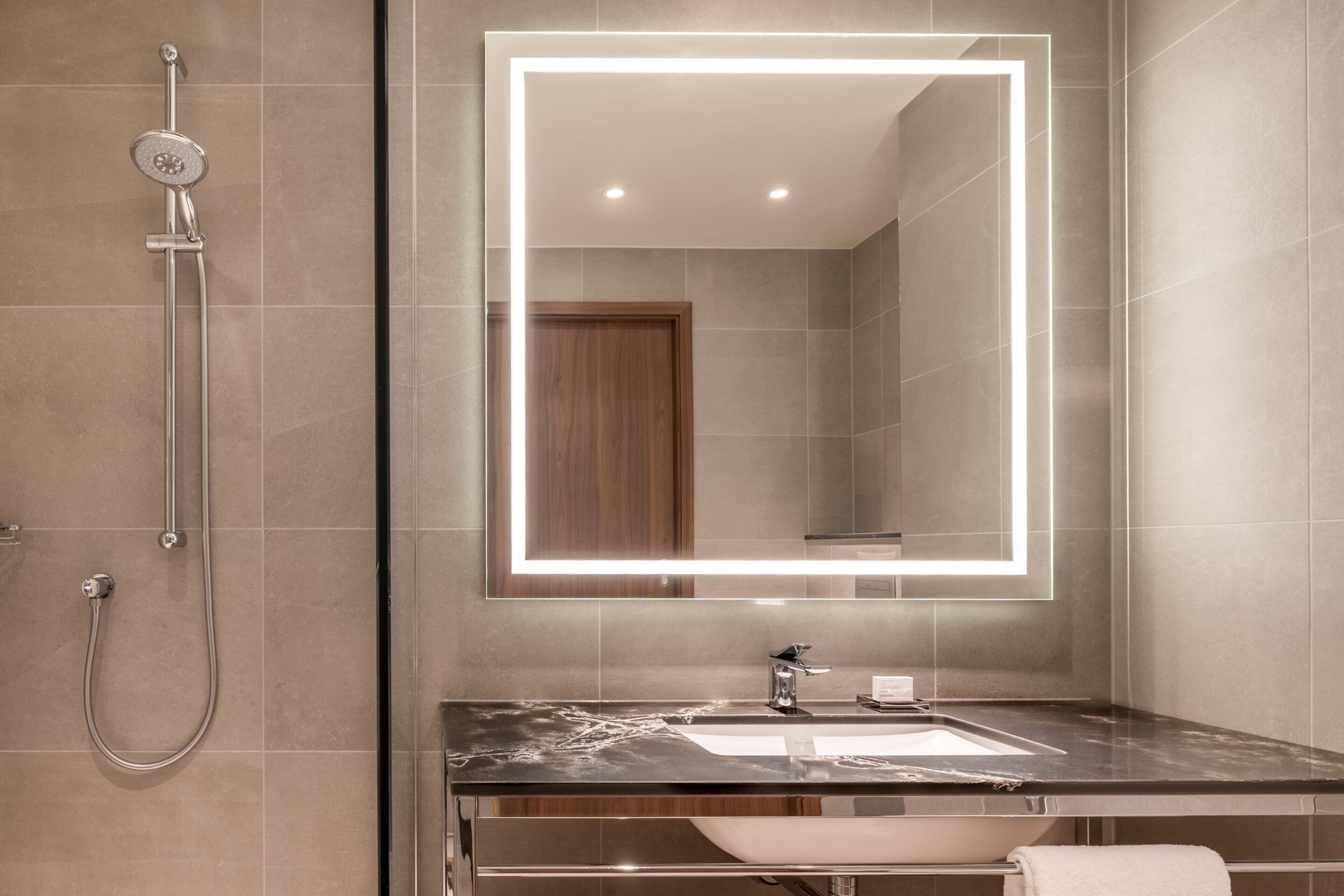 Une salle de bain moderne avec un grand miroir, une douche et un lavabo.