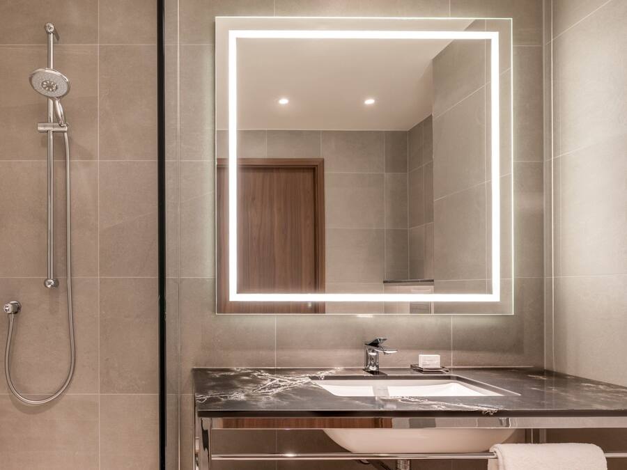 Ein modernes Badezimmer mit einem großen Spiegel, einer Dusche und einem Waschbecken.