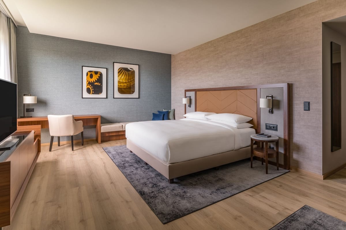 Une chambre d’hôtel moderne avec un grand lit, un bureau, une chaise et des œuvres d’art accrochées au mur.