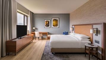 Une chambre d’hôtel moderne avec un grand lit, un bureau, une télévision et des œuvres d’art accrochées au mur.