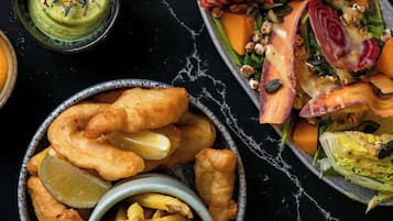 Diversi piatti, tra cui fish and chips, un'insalata e un cestino di patatine fritte.