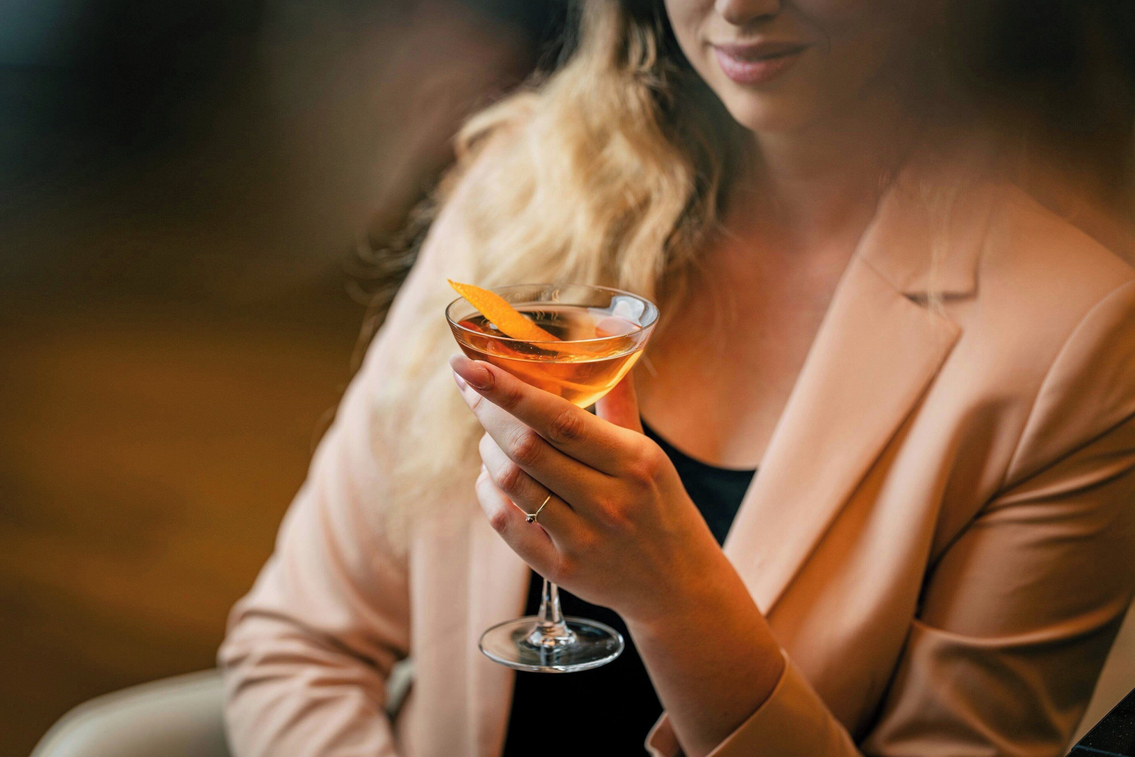 Eine Person hält ein Cocktailglas mit Orangenscheibe.