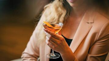 Eine Person hält ein Cocktailglas mit Orangenscheibe.