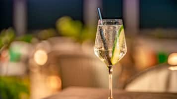 A glass of cocktail with a straw on a coaster, placed on a table.