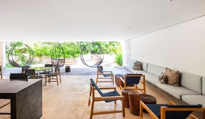 A modern outdoor seating area with wicker chairs, a round table, and a sofa. - IIK Tulum by The Spot Rentals (Tulum)