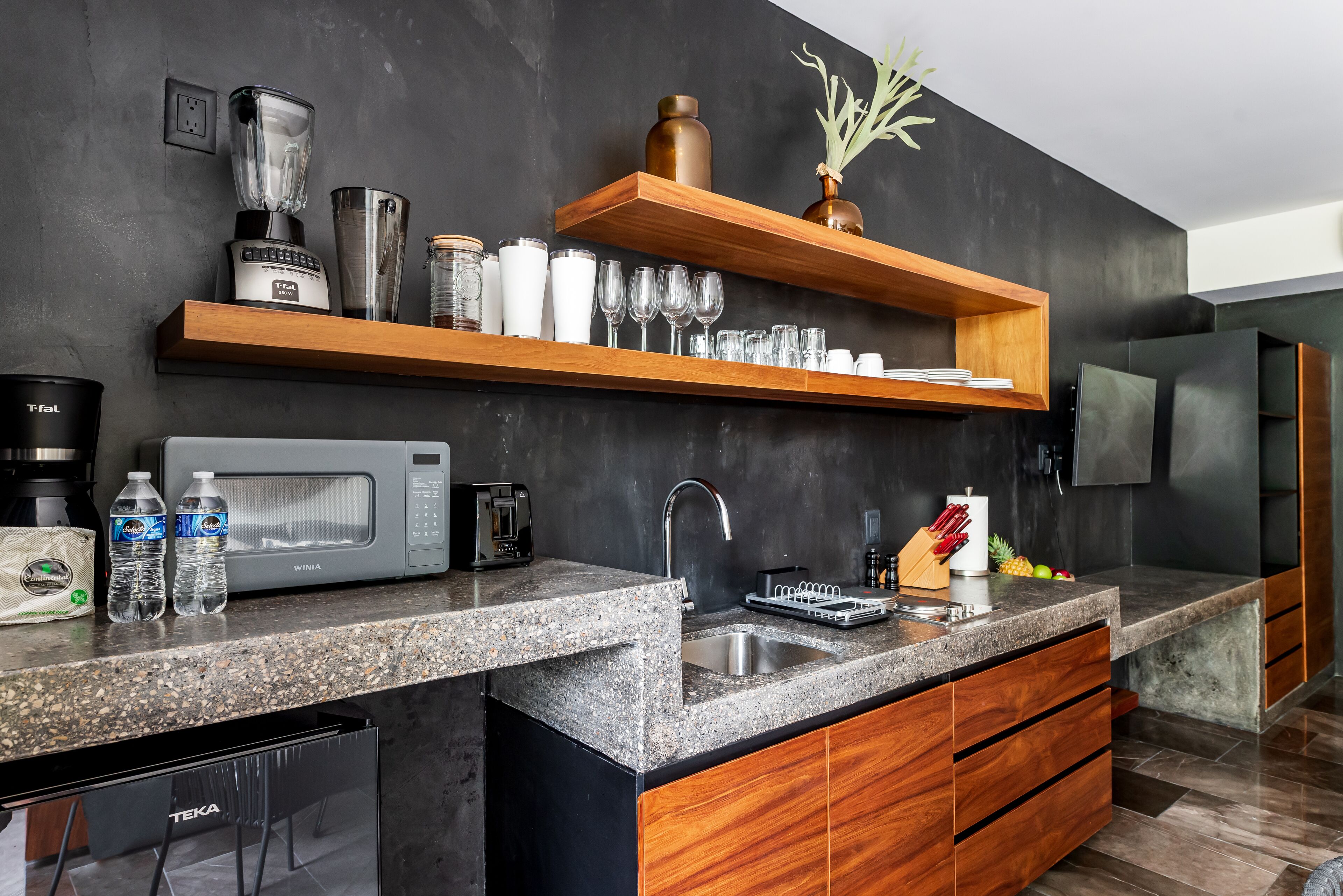 A modern kitchen with granite countertops, wooden cabinets, a built-in microwave, and a stainless steel sink.