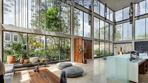 A spacious lobby with large windows, a reception desk, and seating areas. - IIK Tulum by The Spot Rentals (Tulum)