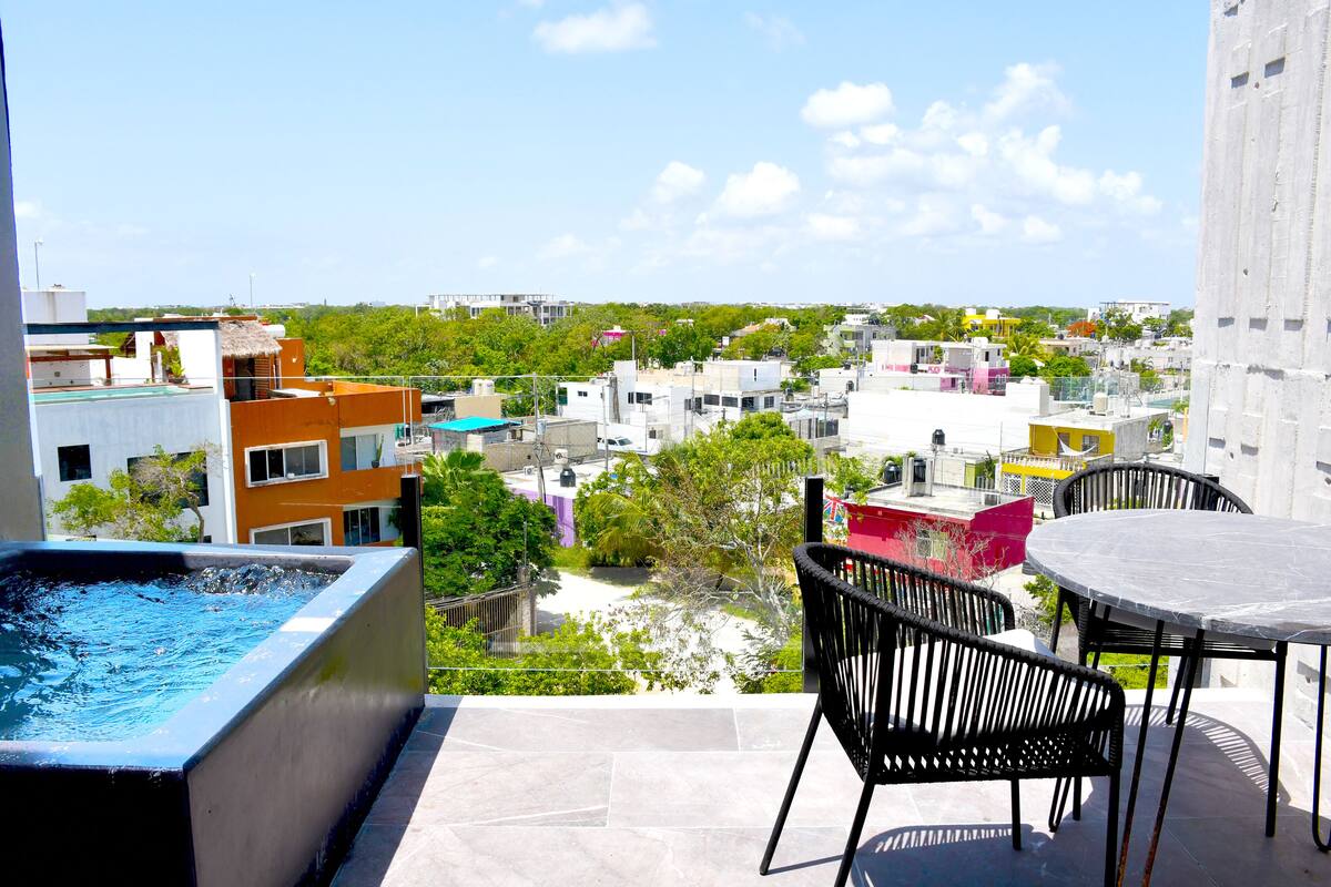 A rooftop terrace with a swimming pool, outdoor seating, and a view of a cityscape.