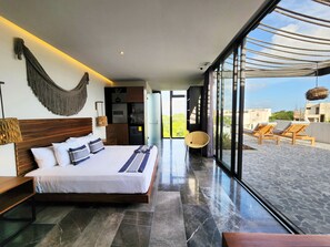A modern bedroom with a large bed, a wooden headboard, and a view of the outdoor terrace.