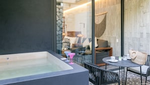 A modern bathroom with a bathtub, a glass-enclosed shower area, and a seating area with a table and chairs. - IIK Tulum by The Spot Rentals (Tulum)