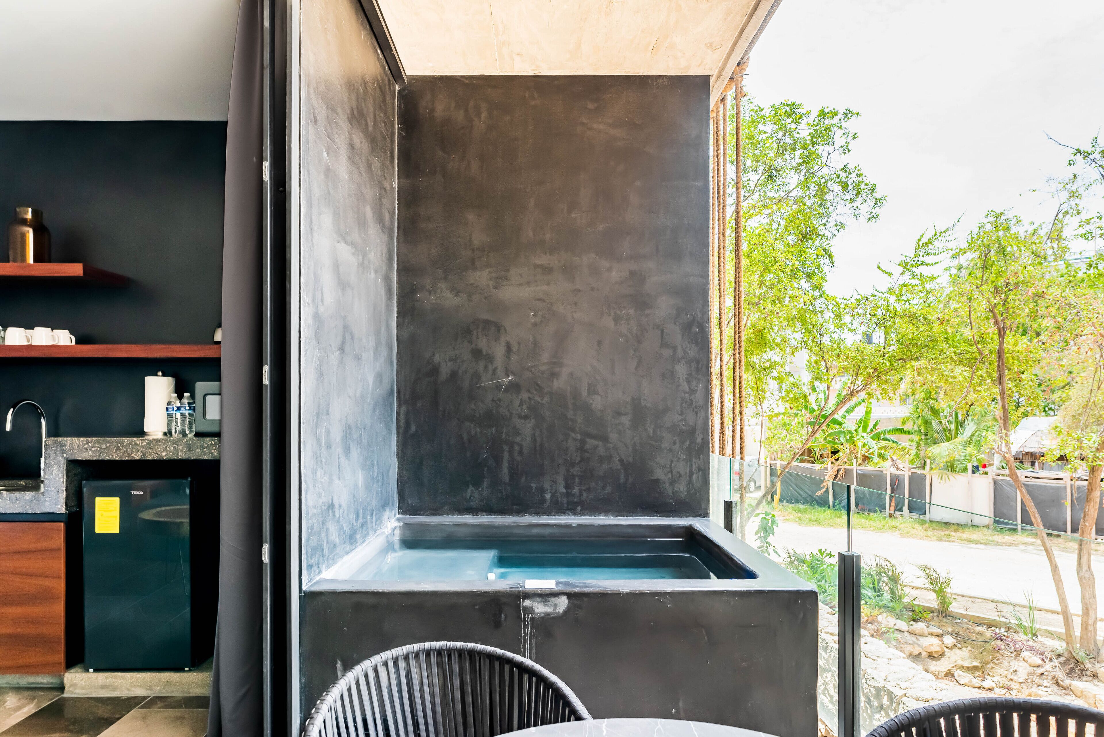 A modern kitchen with a built-in sink, a refrigerator, and a window overlooking a garden.