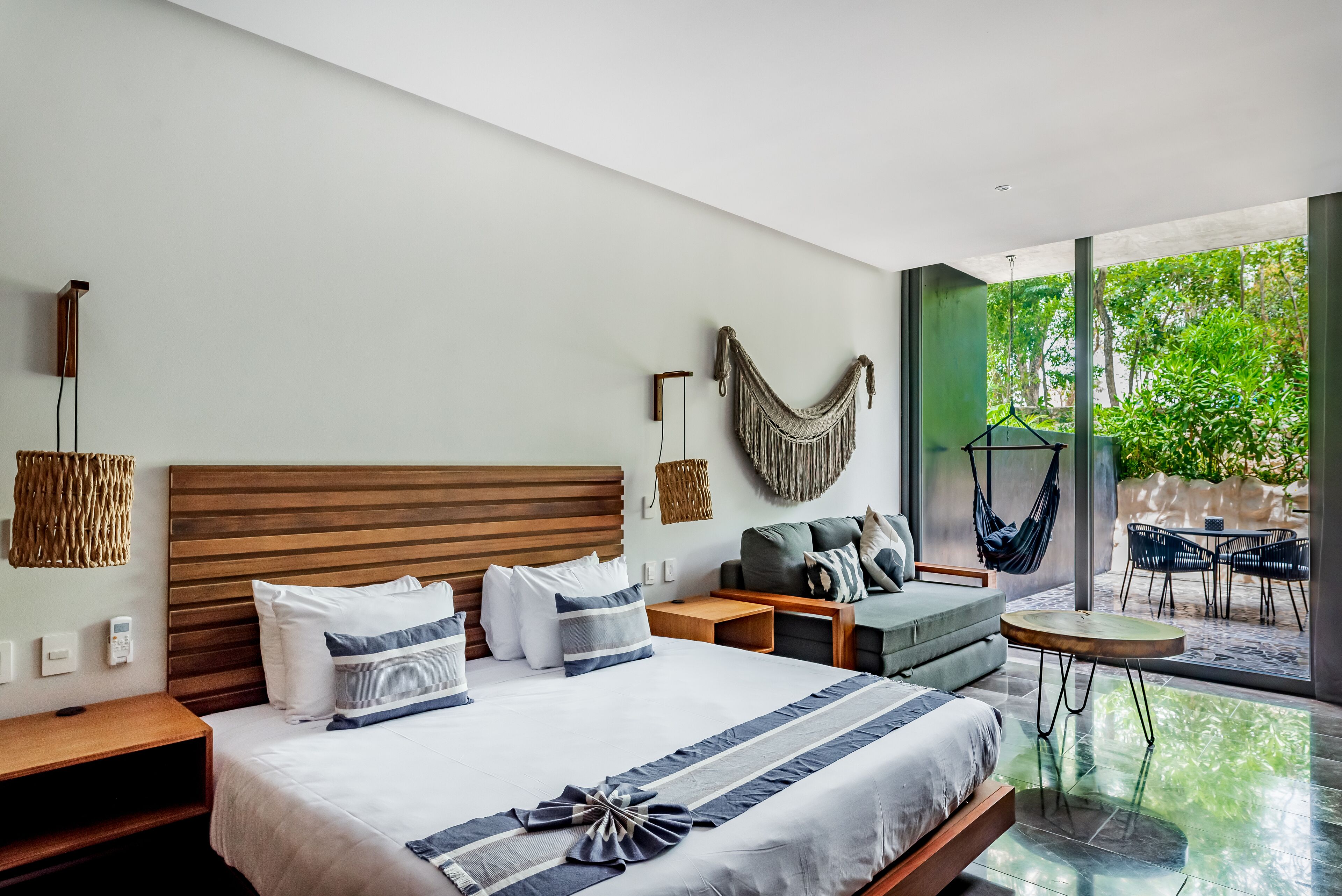 Une chambre d’hôtel moderne, dotée d’un grand lit, d’un canapé, d’une petite table et offrant une vue sur l’extérieur.