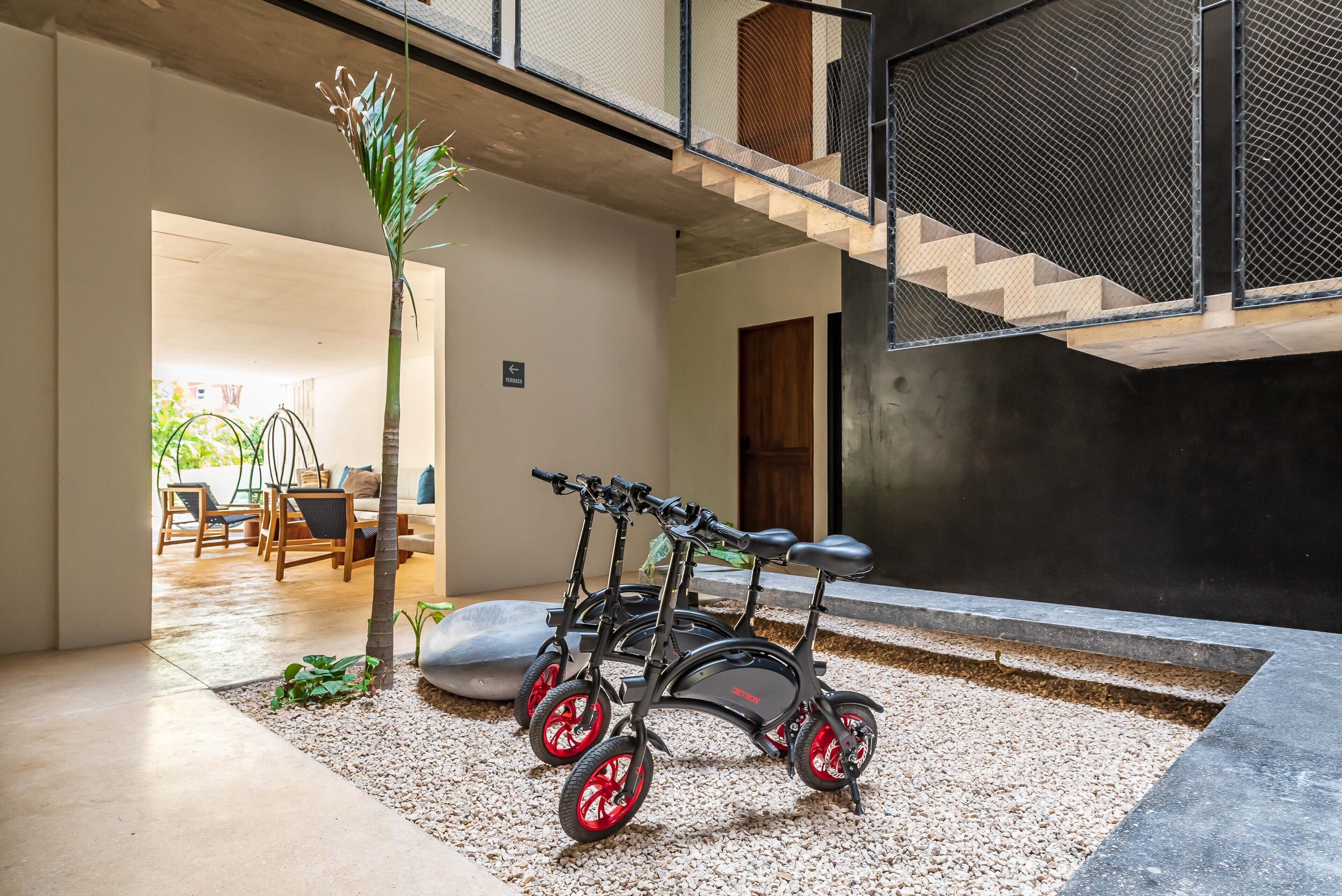 A modern interior with a staircase, a seating area with chairs, and a tricycle.