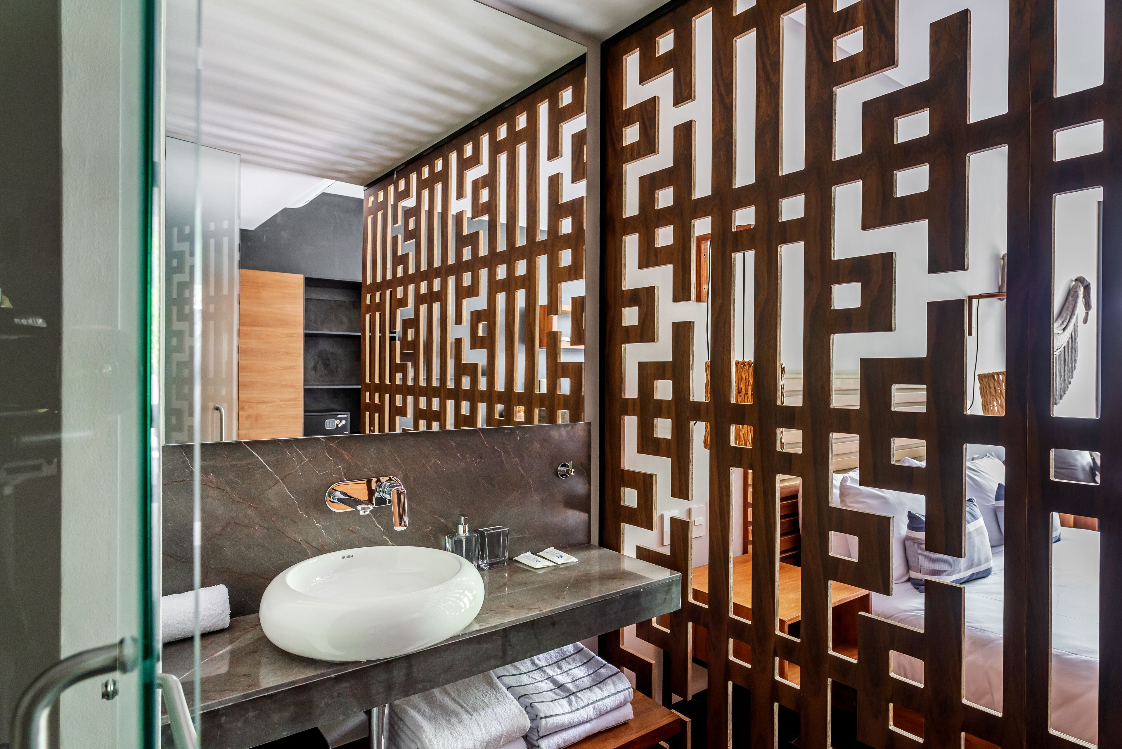 A modern bathroom with a glass partition, a marble sink, and a wooden panel design.