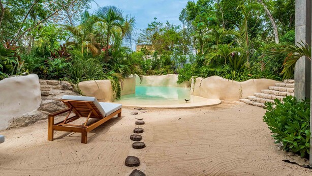 A serene outdoor spa area with a wooden lounge chair, a small pool, and a stone pathway. - IIK Tulum by The Spot Rentals (Tulum)