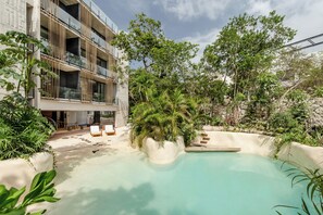 A modern building with a pool, surrounded by lush greenery and outdoor seating. - IIK Tulum by The Spot Rentals (Tulum)
