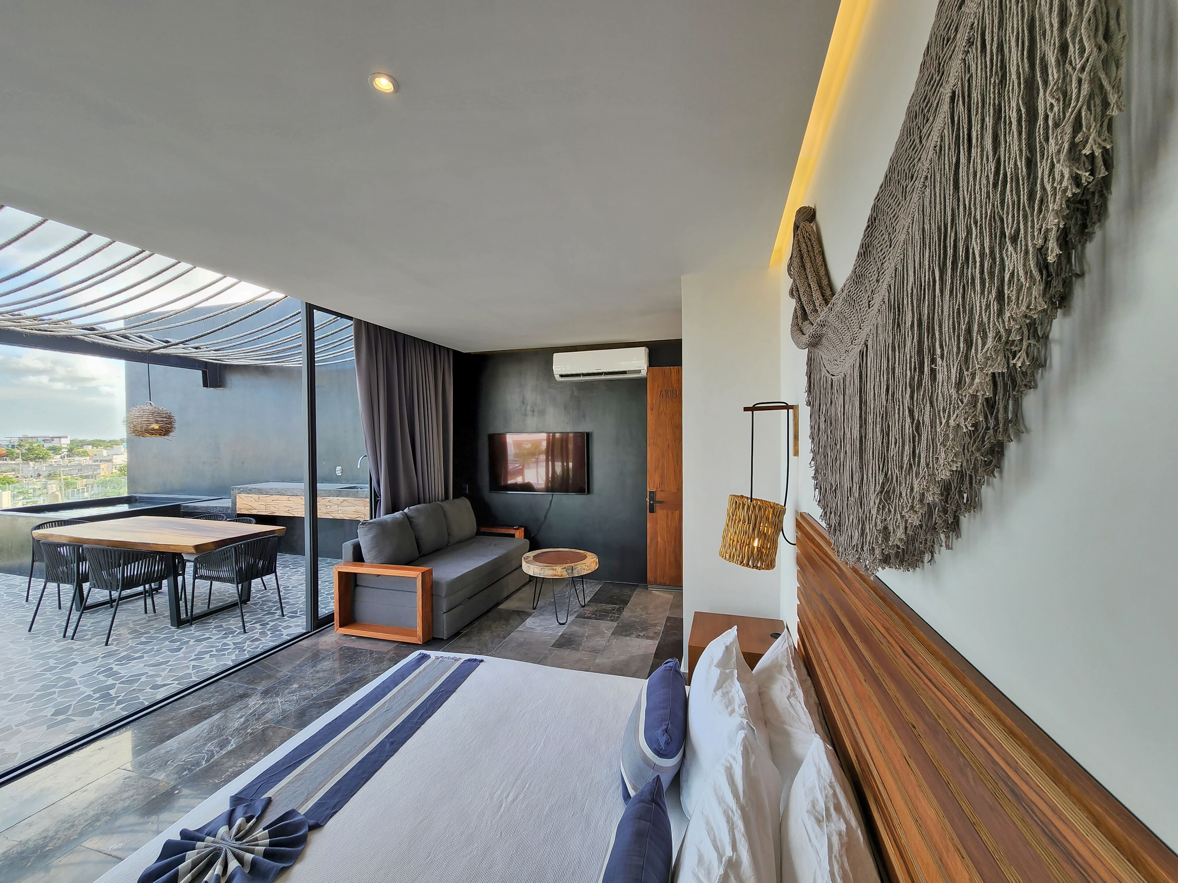 A modern living room with a sofa, a dining table, and a large window offering a city view.