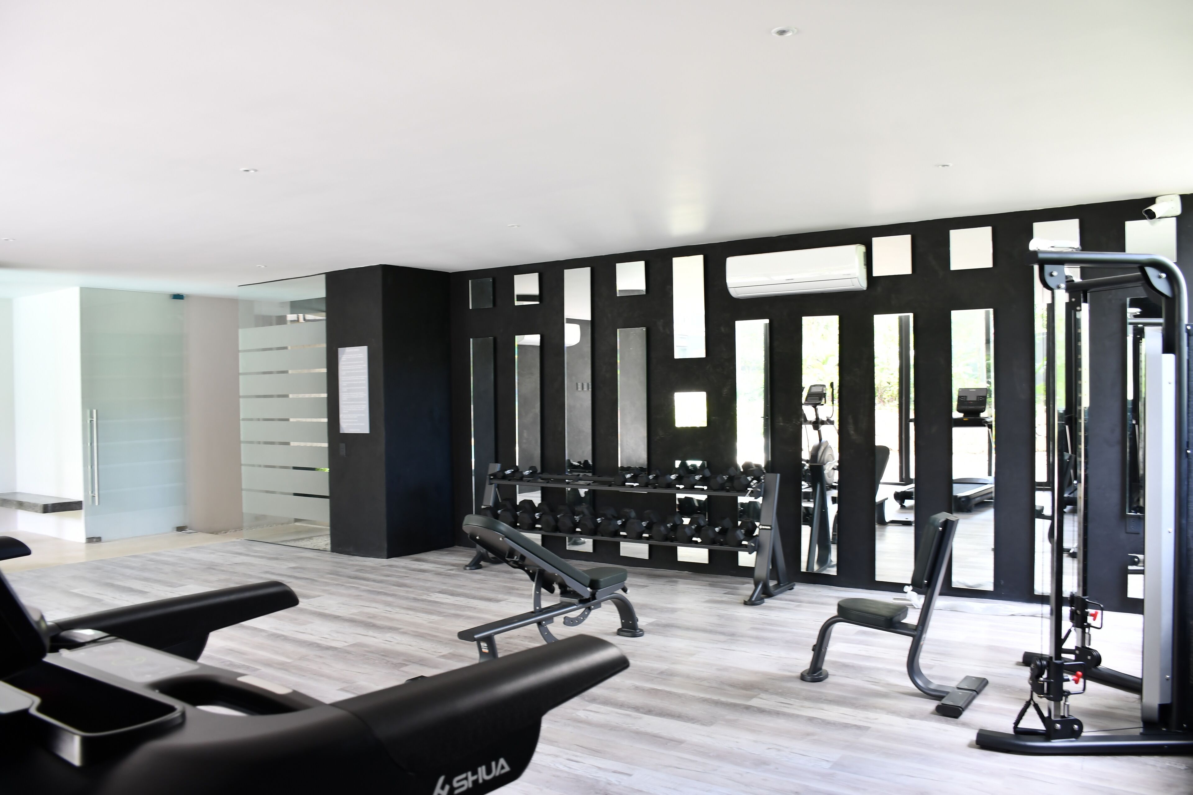 A modern gym with treadmills, weight machines, and dumbbells.