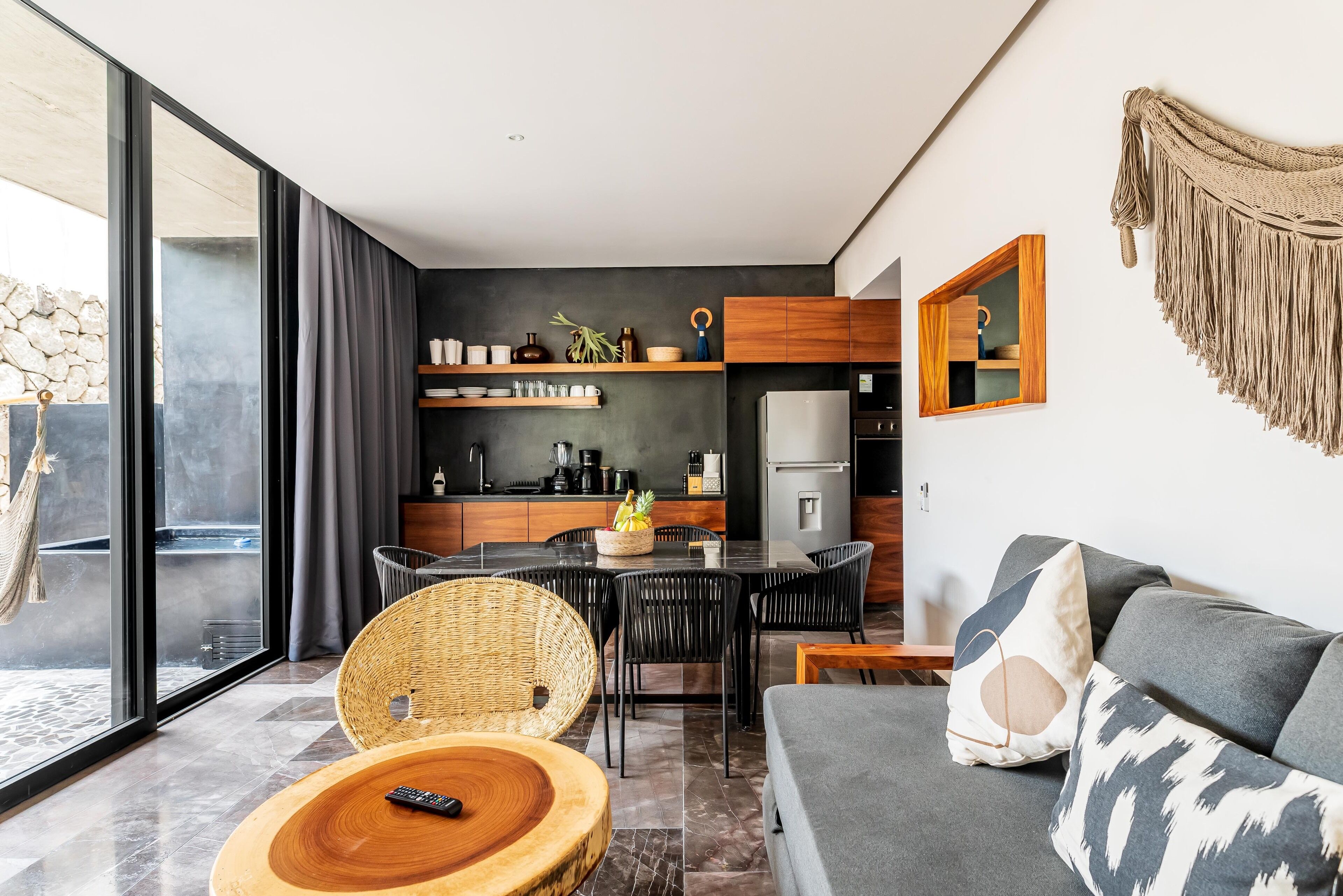 A modern living room with a sofa, a dining table, and a kitchen area in the background.