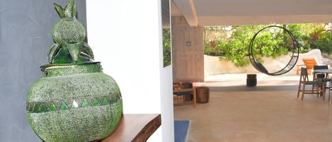 Un vase décoratif vert posé sur une étagère en bois, un hamac et un espace patio avec des chaises et une table.