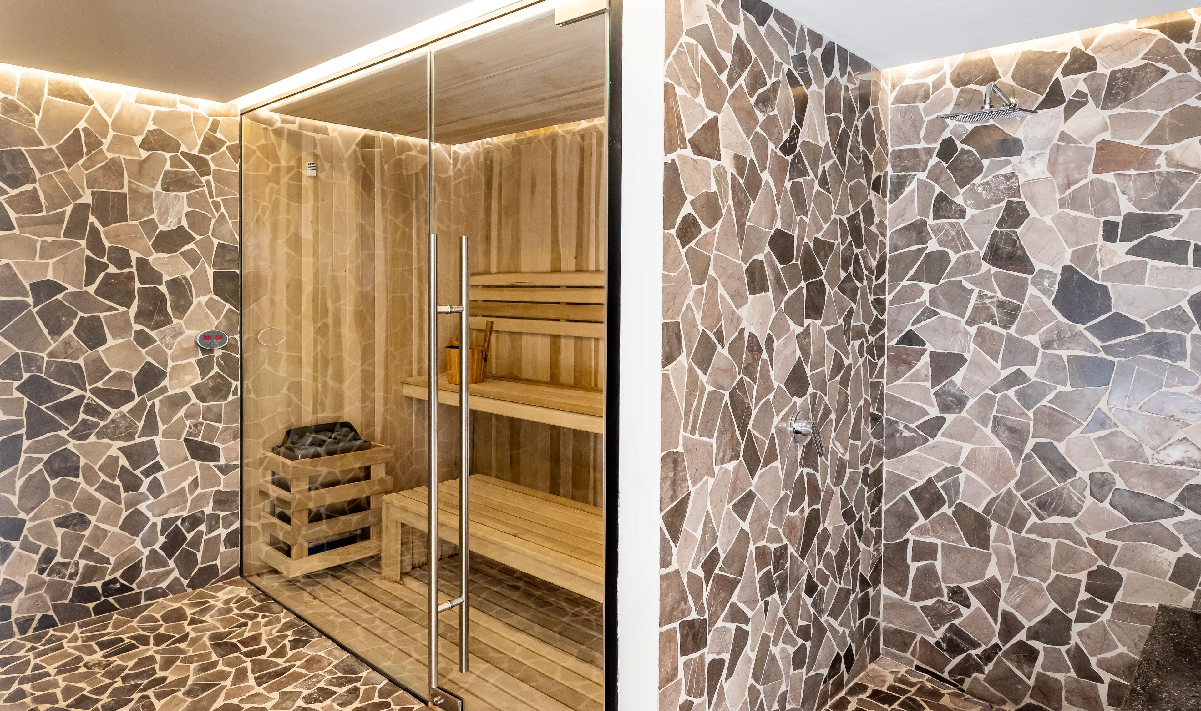 Un espacio de ducha moderno con paredes de mosaicos y un banco de madera.