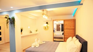 A modern hotel room with a bed, a bedside table, a mirror, and a wall-mounted shelf with plants. - Gikas Apartments - Serenity Suite (Corfu)