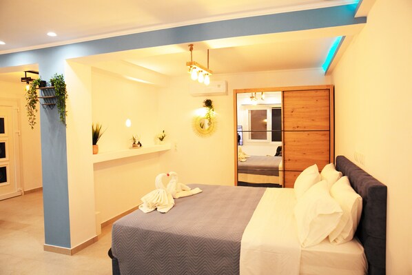 A modern hotel room with a bed, a bedside table, a mirror, and a wall-mounted shelf with plants.