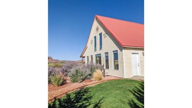 A single-story building with a red roof, white siding, and a small porch. - Homestead Hideaway- Spacious Home Central to Zion, Grand Canyon, Bryce & More! (Cane Beds)