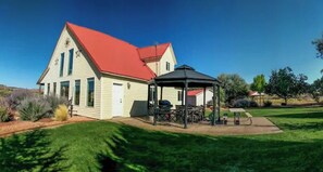 A house with a red roof, a covered patio with outdoor furniture, and a well-maintained lawn.