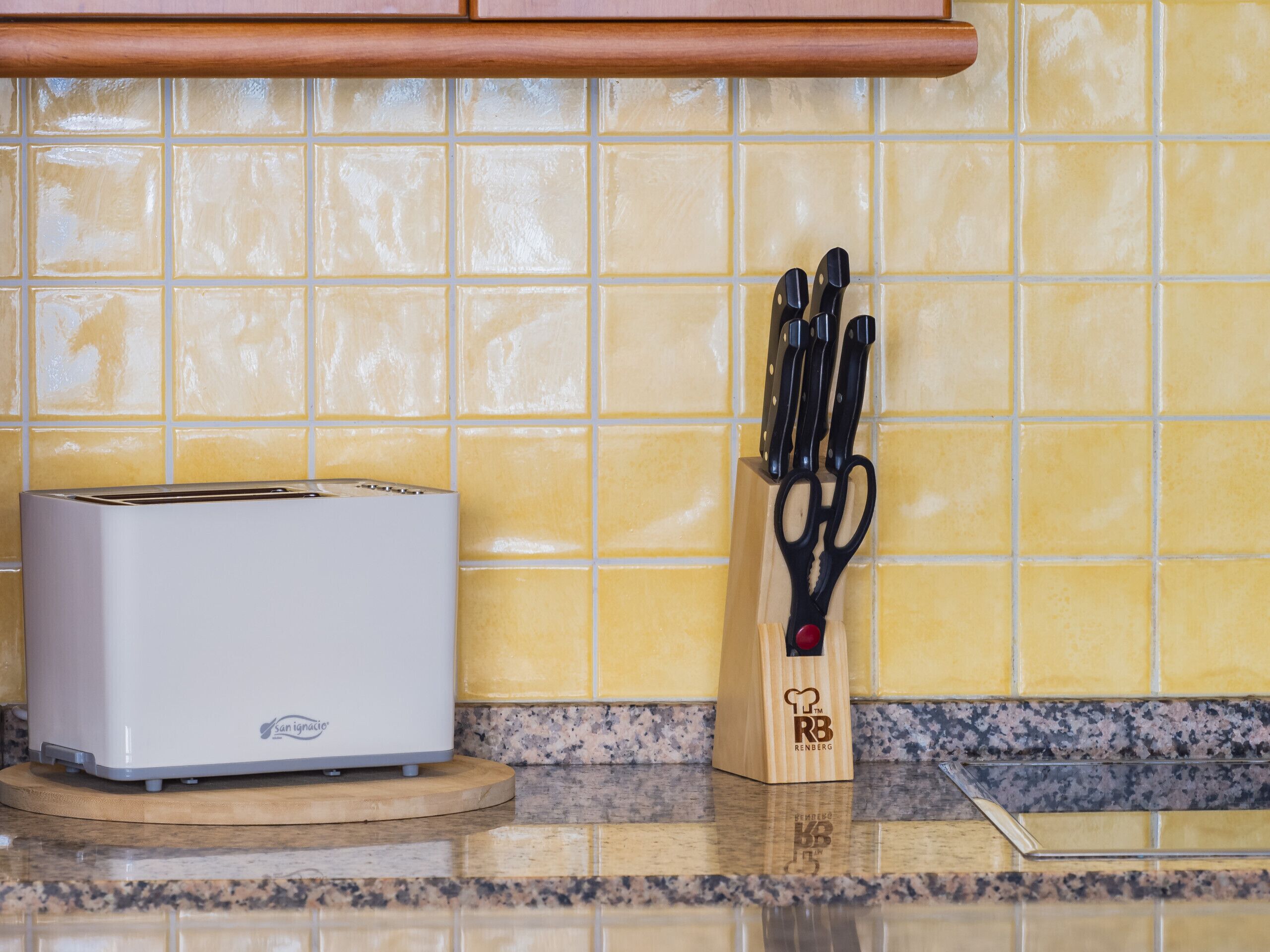 Un plan de travail de cuisine avec un grille-pain, un bloc à couteaux et un pare-éclaboussures.
