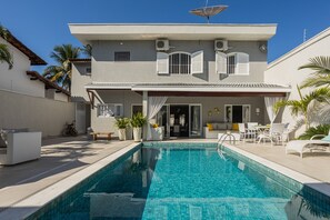 Ett modernt hus med en swimmingpool, utemöbler och en uteplats.